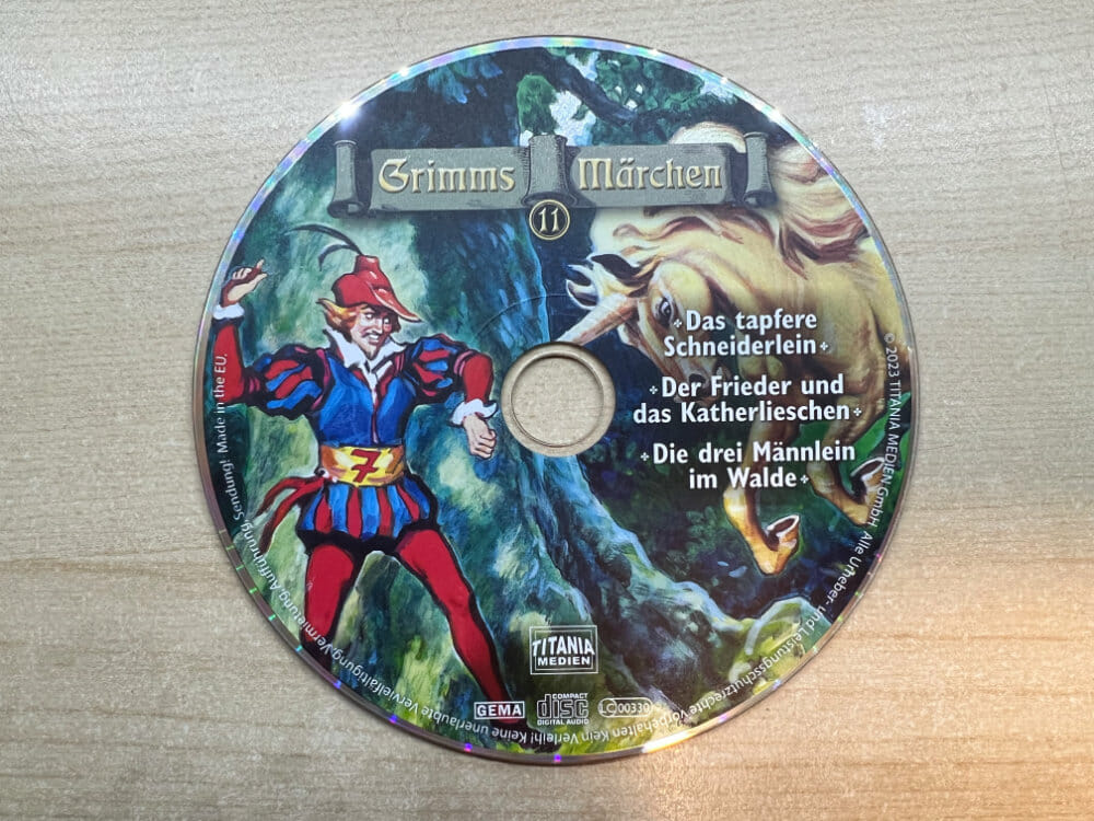 Auf diesem Bild ist das Design der CD zu sehen. Im Wesentlichen bildet die CD das Artwork des Hüllen-Covers mit dem tapferen Schneiderlein hinter einem Baum und das heranstürmende Einhorn ab.